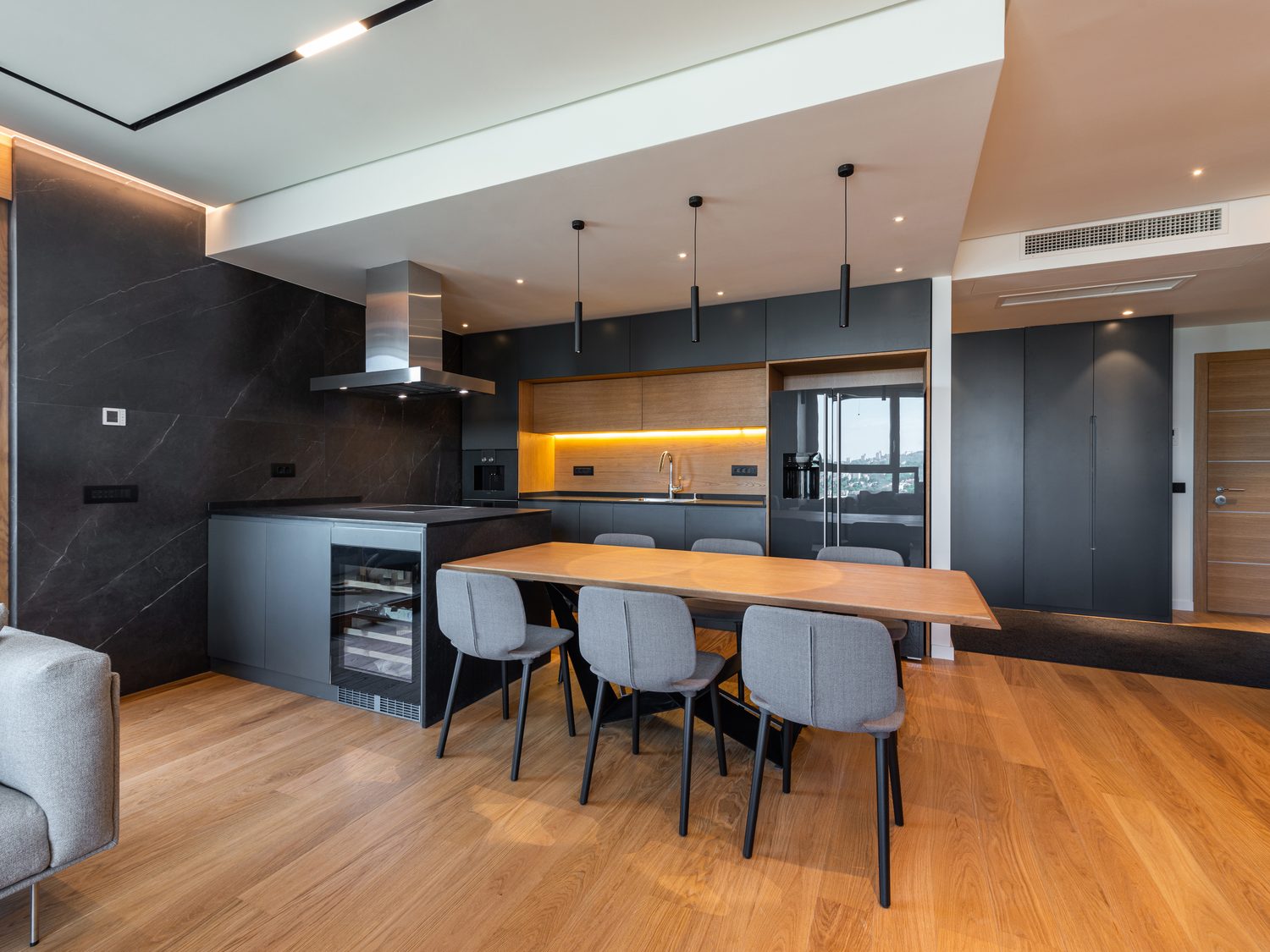 Muestra de estilo: cocina de diseño oscura con mesa de madera y luz cálida.